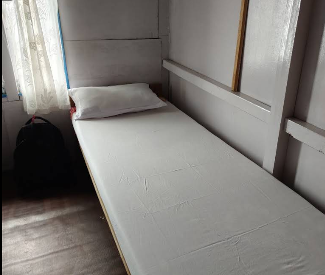 A clean simple bed in a room at Hotel Magnificent
